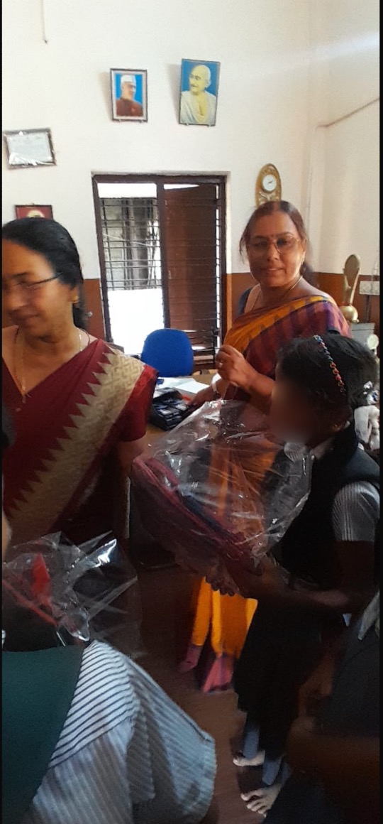 Young girl receiving a backpack from teachers
